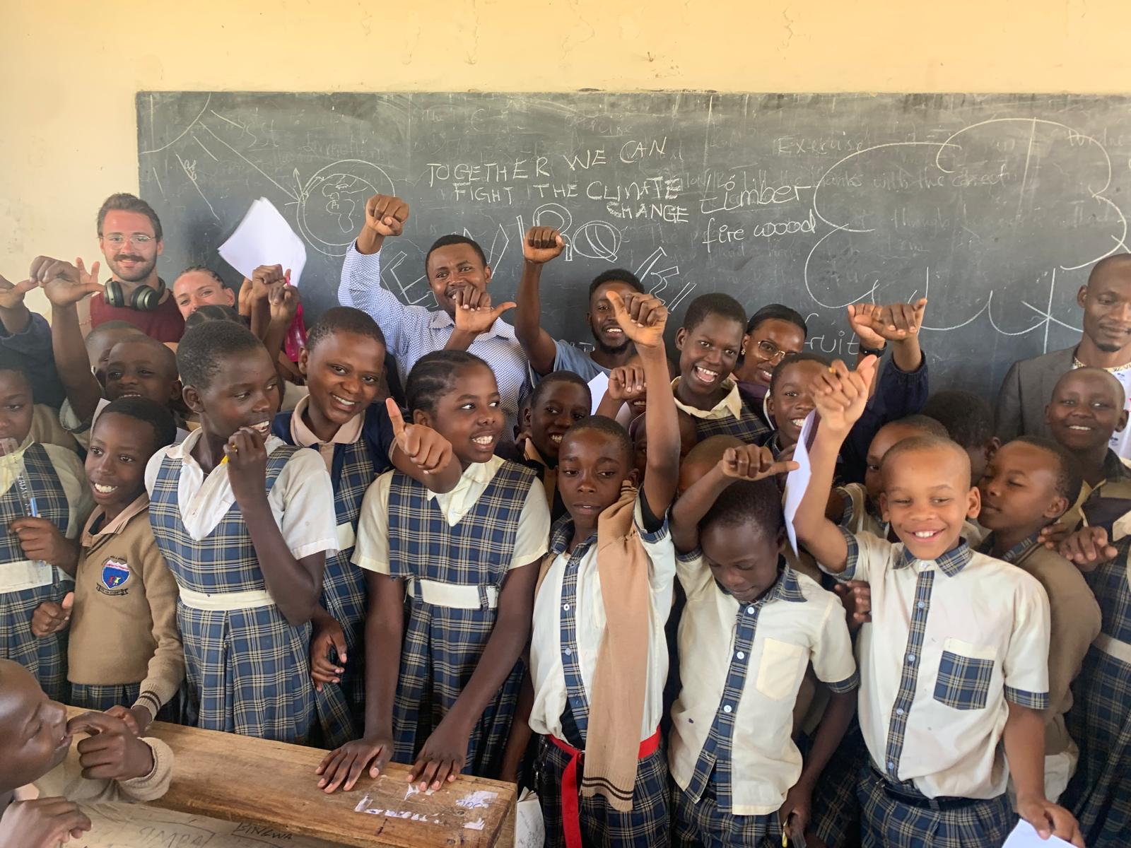 Enviro Kids students cheering at a classroom chalkboard that reads 'Together we can fight the climate change'